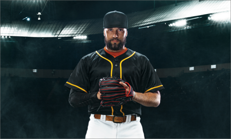 Baseball player in a black and yellow jersey holding a glove, standing in a stadium under bright lights.